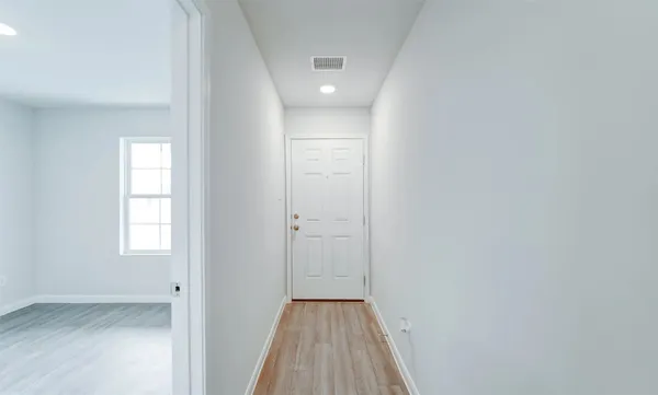 a view of a hallway with wooden floor and a window