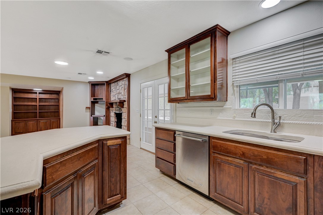 7631 Bermuda Road Las Vegas, NV 89123 - Photo 19 of 64 A well-appointed kitchen featuring a stainless steel dishwasher, ample cabinetry, and a cozy fireplace nearby.