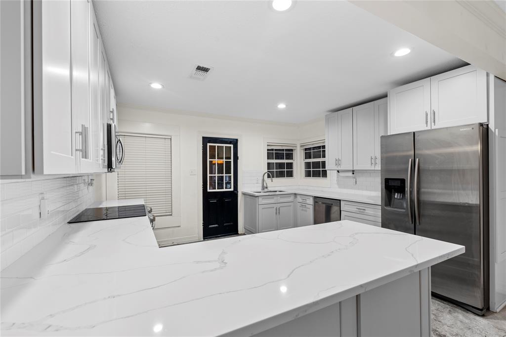 a kitchen with stainless steel appliances kitchen island a refrigerator sink and cabinets