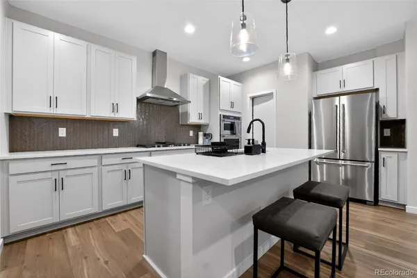 a kitchen with stainless steel appliances a sink a stove a refrigerator cabinets and chairs