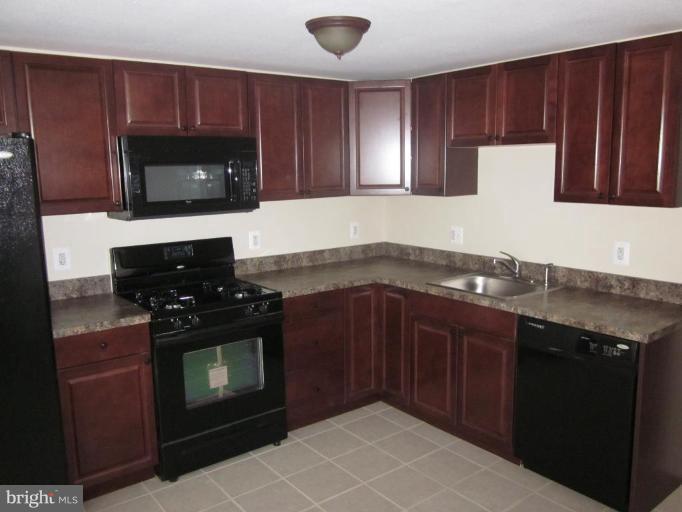 1120 North Point Road Dundalk, MD 21222 - Photo 11 of 14 a kitchen with granite countertop a stove top oven microwave and cabinets