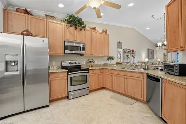 a kitchen with granite countertop a refrigerator a sink a stove top oven and cabinets