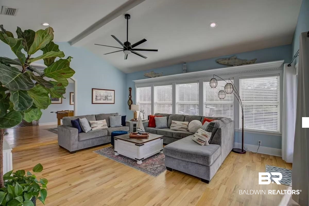 16297 Honey Road Summerdale, AL 36580 - Photo 8 of 24 Spacious living area featuring a vaulted ceiling with exposed beams, light wood-finish flooring, a contemporary ceiling fan, and extensive natural light from multiple windows