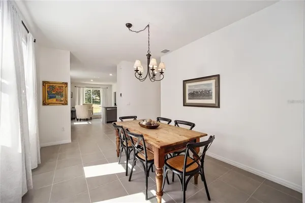 a dining room with wooden floor a chandelier a wooden table and chairs