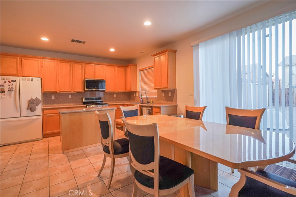 15133 Pasture Way Victorville, CA 92394 - Photo 13 of 48 a dining room with furniture a large window and stainless steel appliances
