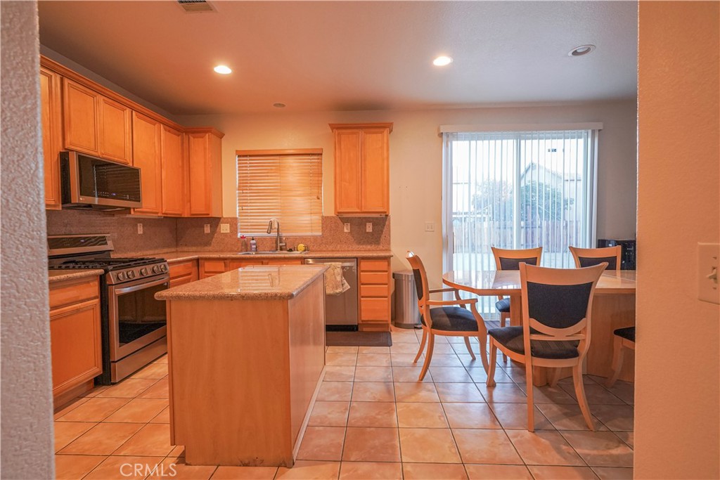 15133 Pasture Way Victorville, CA 92394 - Photo 17 of 48 a kitchen with stainless steel appliances granite countertop a stove a sink a microwave dining table and chairs