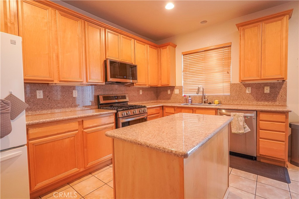 15133 Pasture Way Victorville, CA 92394 - Photo 18 of 48 a kitchen with stainless steel appliances granite countertop a sink a stove and a refrigerator