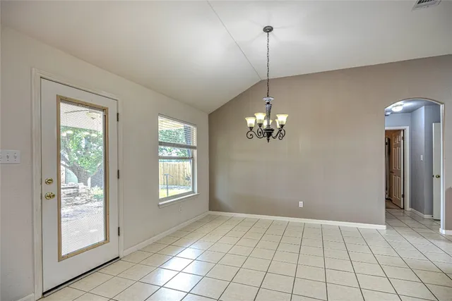 a view of an empty room with window and chandelier fan