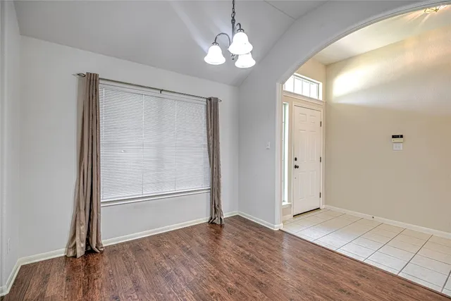an empty room with wooden floor cabinet and windows