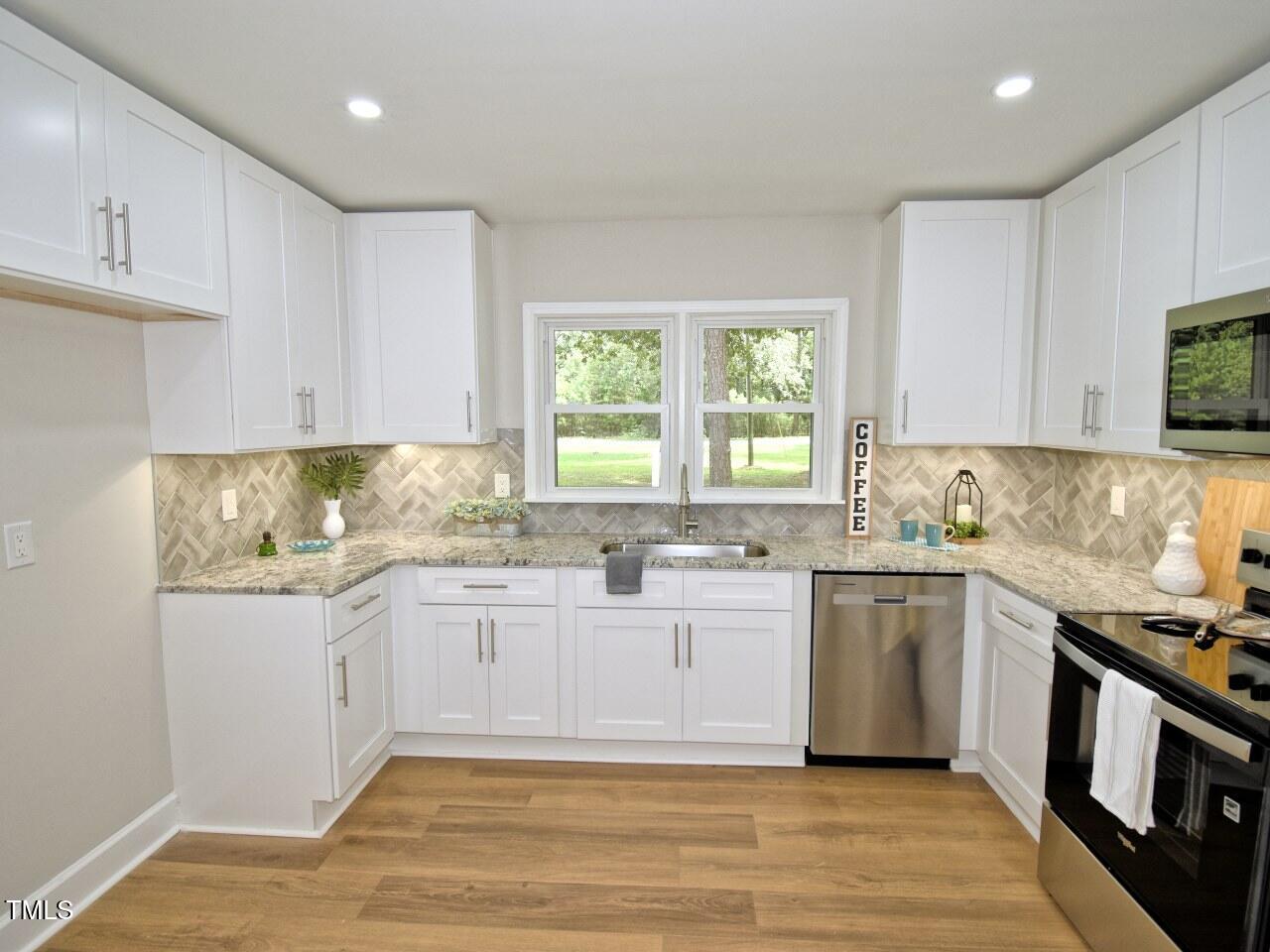 906 Perry Road Zebulon, NC 27597 - Photo 7 of 36 a kitchen with stainless steel appliances granite countertop a stove a sink and white cabinets