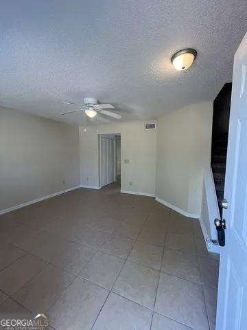 a view of an empty room and chandelier fan