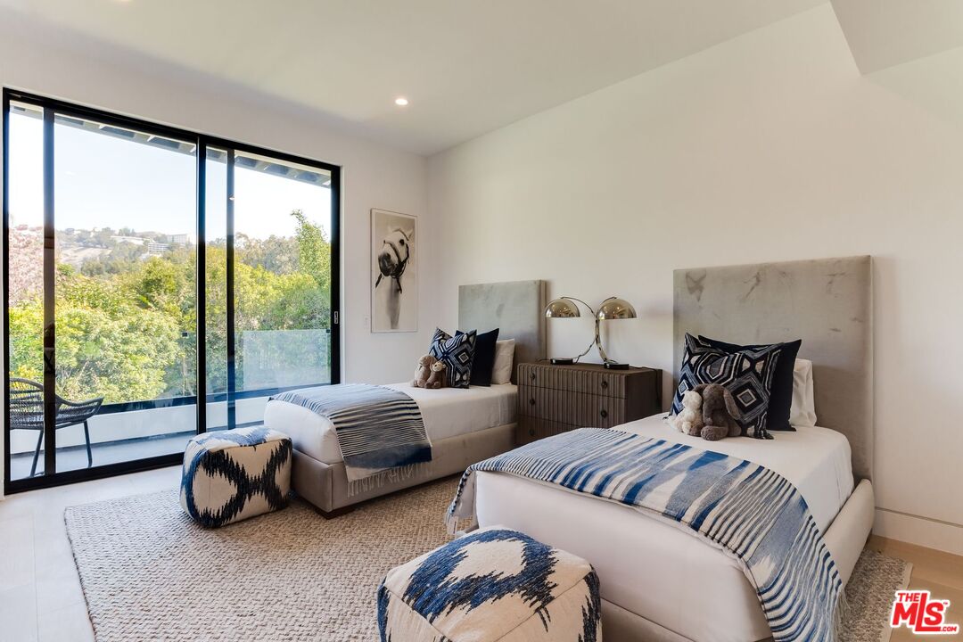 12119 Travis Street Los Angeles, CA 90049 - Photo 12 of 26 a spacious bedroom with a bed and a couch next to a window