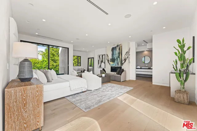 a living room with furniture large window and potted plants