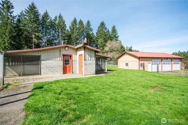 a view of a yard in front of a house with plants and large tree