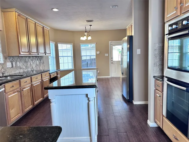 a view of an empty room with wooden floor fireplace and a window