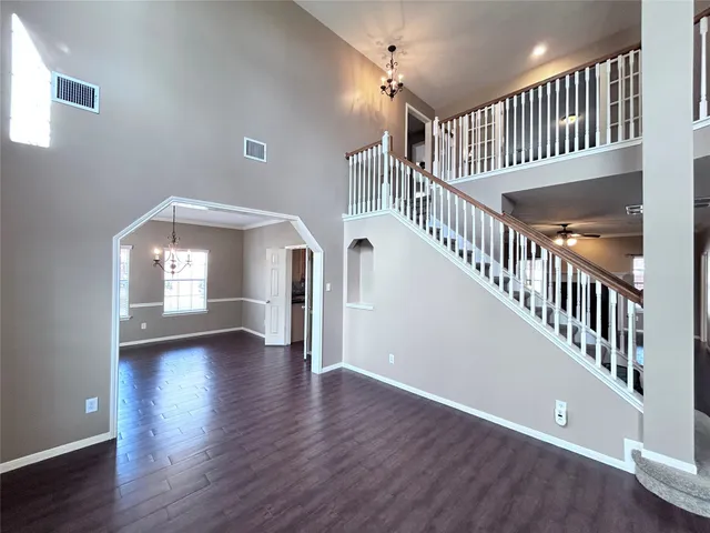 an empty room with wooden floor ceiling fan and window