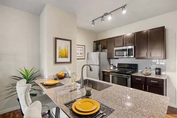 a kitchen with stainless steel appliances granite countertop a stove a sink dishwasher a dining table and chairs with wooden floor