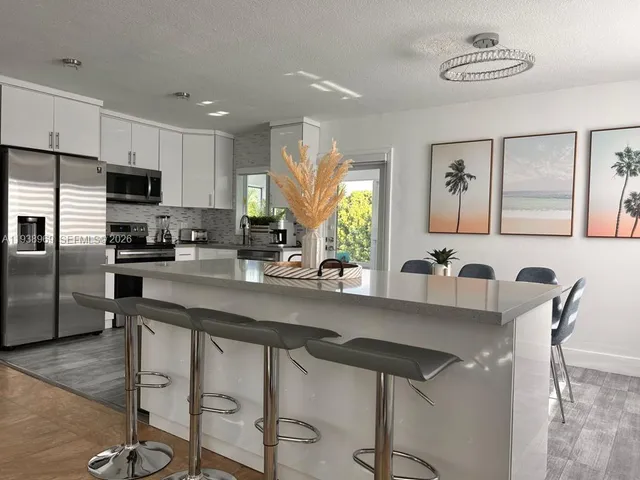 a kitchen with granite countertop a counter space dining table stainless steel appliances and a window