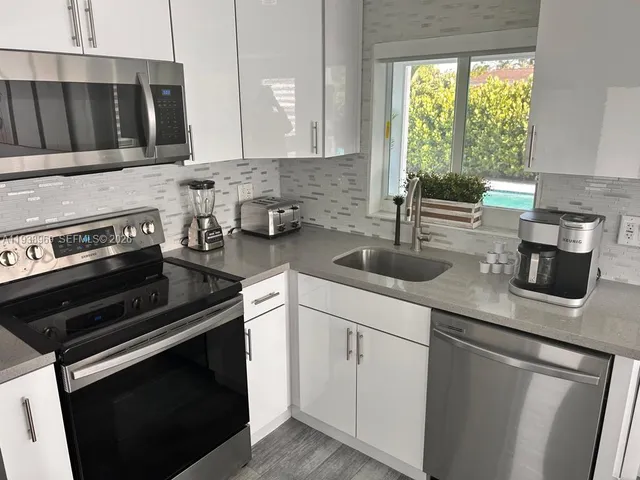 a kitchen with appliances a sink and cabinets