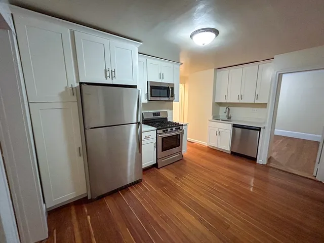a kitchen with wooden floors and stainless steel appliances