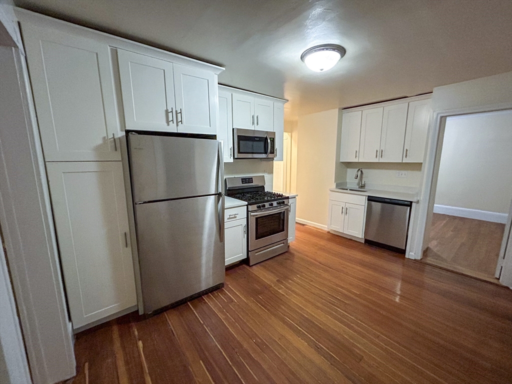 1911 River Street, Unit 2 Boston, MA 02136 - Photo 1 of 16 a kitchen with wooden floors and stainless steel appliances