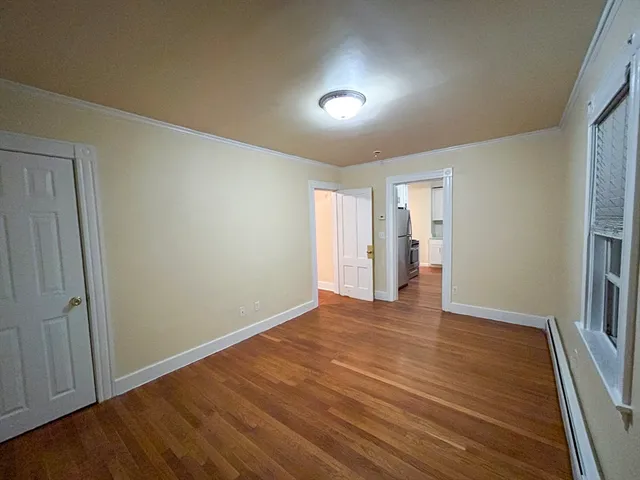 a view of an empty room with wooden floor and closet