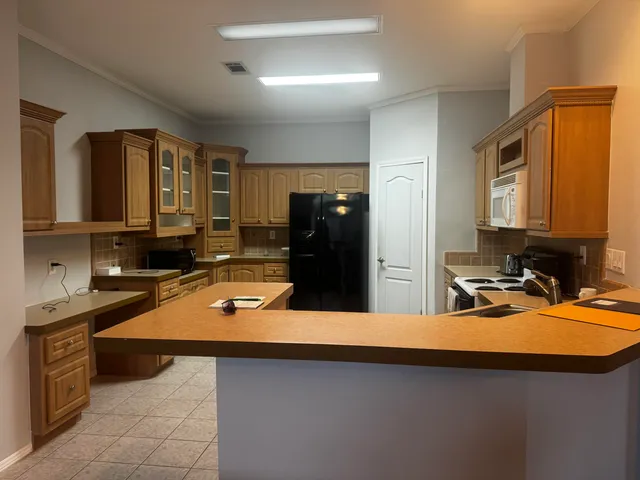 a room with kitchen island a sink a stove and refrigerator