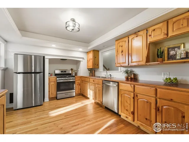 a kitchen with stainless steel appliances granite countertop a refrigerator a stove and a sink with wooden floors