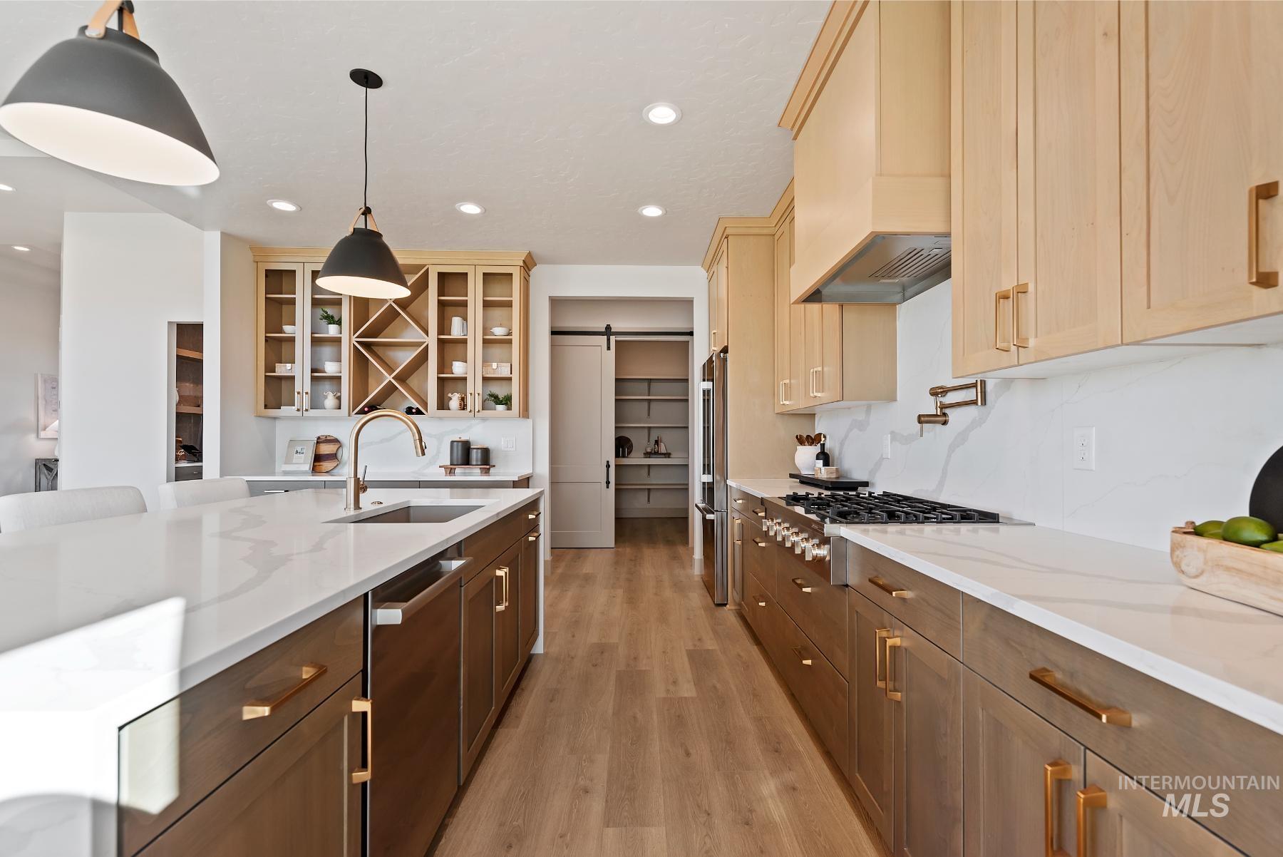 8530 West Graye Street, Unit SHASTA Meridian, ID 83646 - Photo 12 of 28 Kitchen with a barn door, light stone countertops, appliances with stainless steel finishes, light wood finished floors, and glass insert cabinets