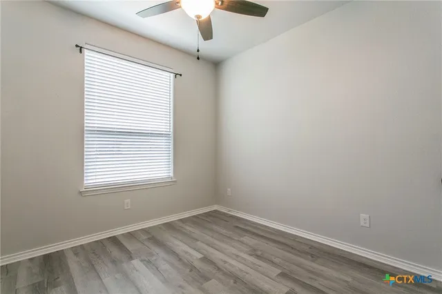 an empty room with a window and wooden floor