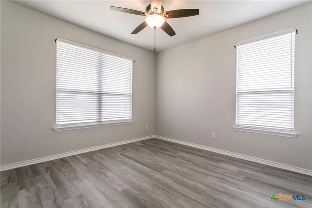 a view of an empty room with window and wooden floor
