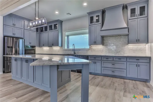 a kitchen with stainless steel appliances granite countertop a sink a stove and a refrigerator