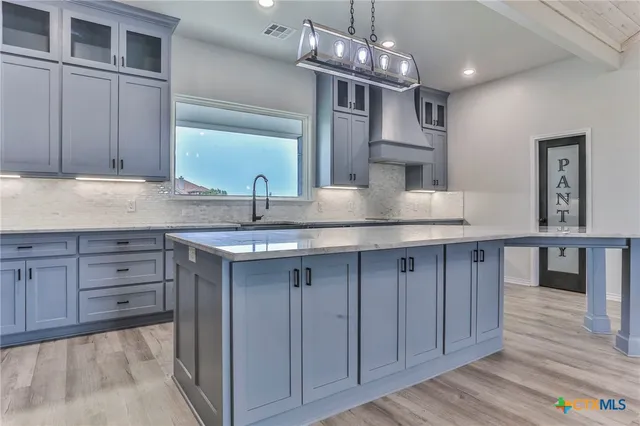 a kitchen with cabinets wooden floor and a chandelier