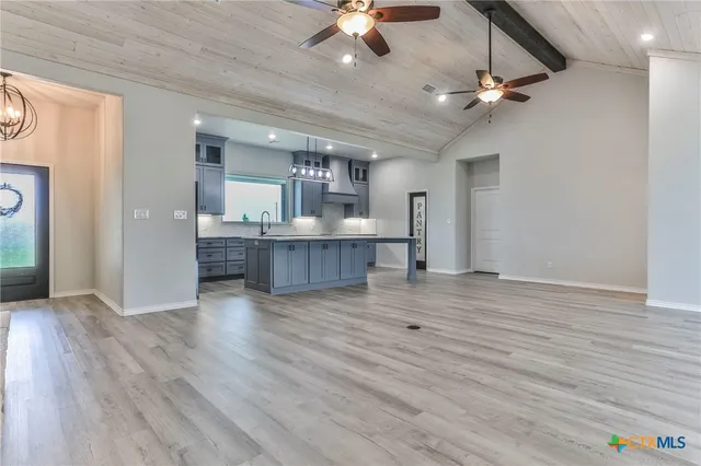 a view of kitchen and empty room with wooden floor