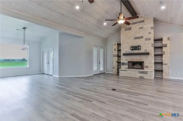 a view of an empty room with wooden floor fireplace and a window