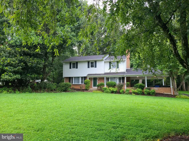 a front view of a house with a garden and trees
