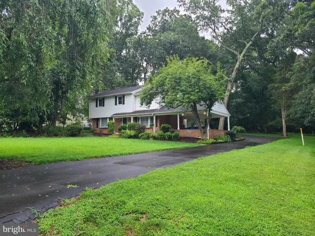 a view of a house next to a big yard and large trees