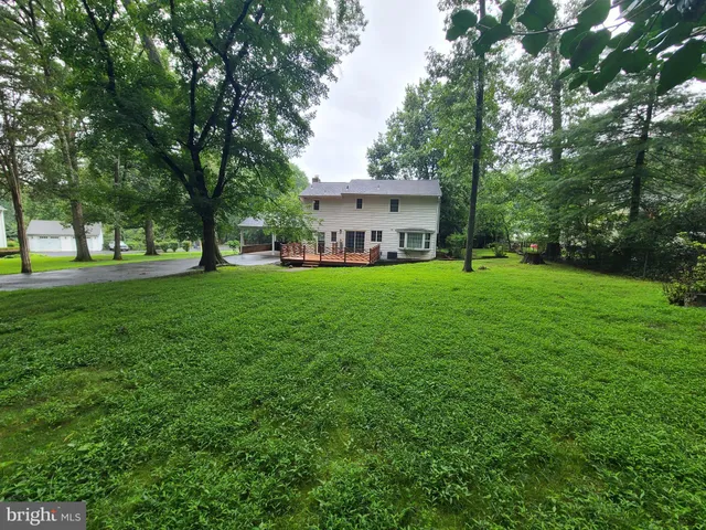 a view of a tiny house with a big yard and large trees