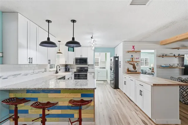 a kitchen with stainless steel appliances kitchen island granite countertop a sink a stove and chairs