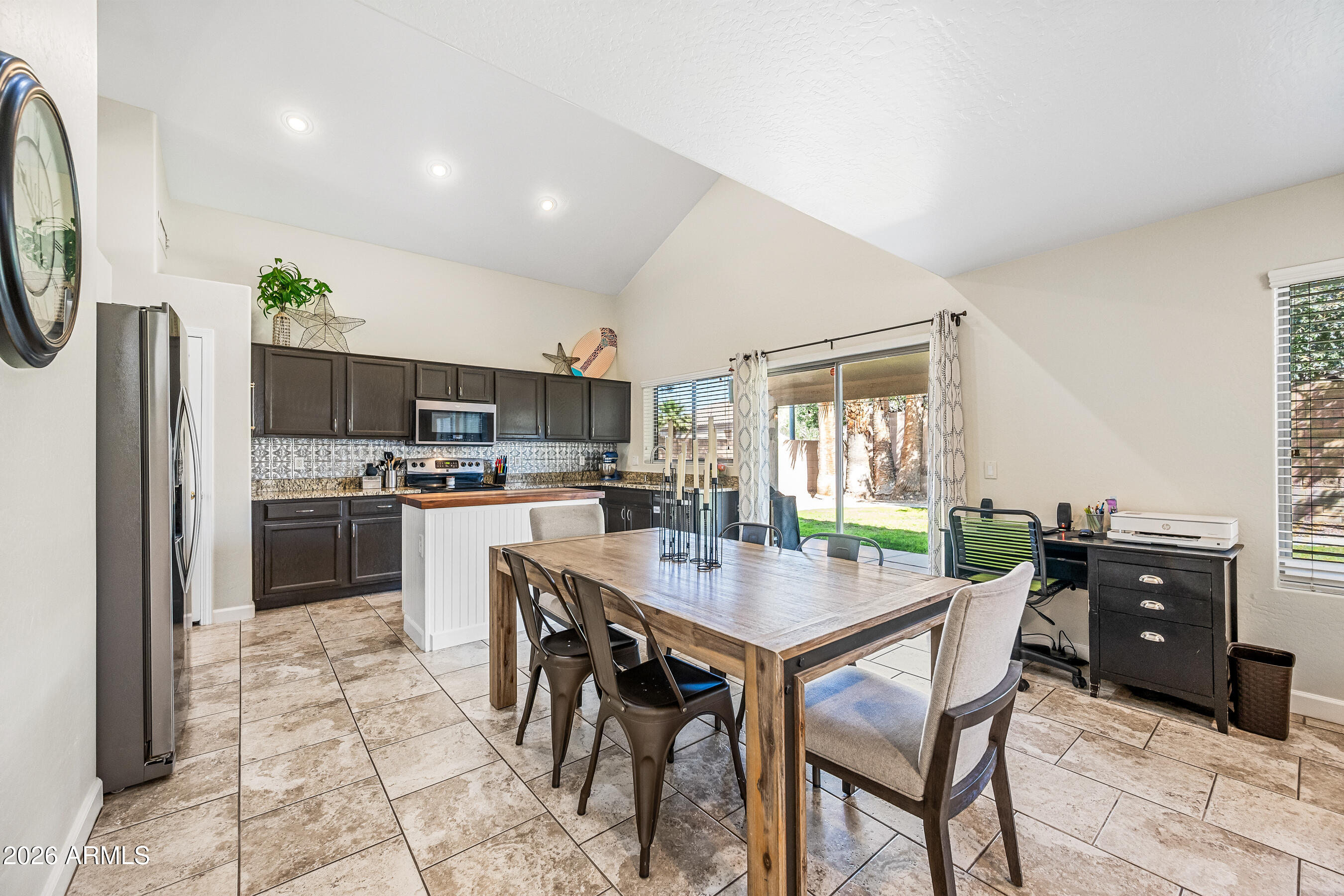 12734 West Cheery Lynn Road Avondale, AZ 85392 - Photo 16 of 54 a kitchen with stainless steel appliances kitchen island granite countertop a refrigerator a stove a microwave oven a sink with island and chairs