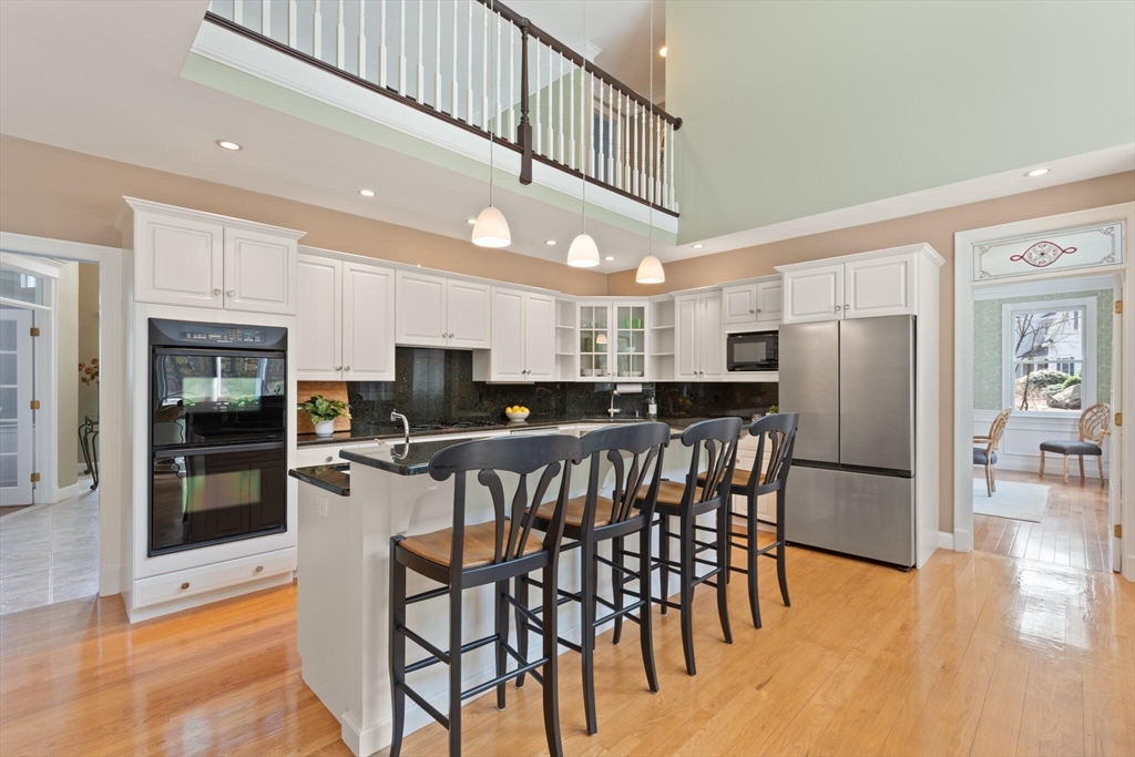 33 Bulkley Road Sudbury, MA 01776 - Photo 12 of 42 a kitchen with stainless steel appliances kitchen island granite countertop a refrigerator a stove a sink a dining table and chairs with wooden floor