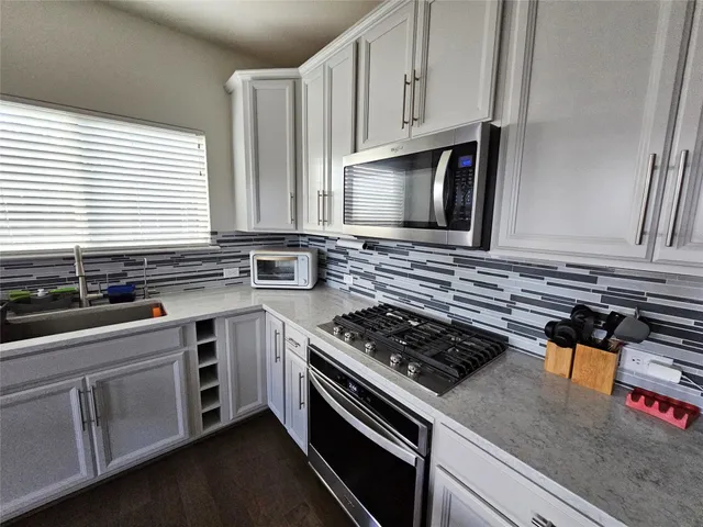 a kitchen with stainless steel appliances granite countertop a sink stove and cabinets