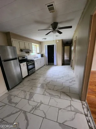 a large kitchen with stainless steel appliances kitchen island granite countertop a refrigerator a stove top oven a sink with a dining table and chairs