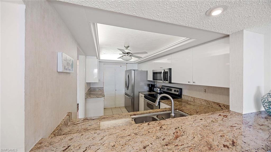 601 Seaview Court, Unit C106 Marco Island, FL 34145 - Photo 11 of 42 Kitchen featuring white cabinets, appliances with stainless steel finishes, light stone counters, a textured ceiling, and ceiling fan