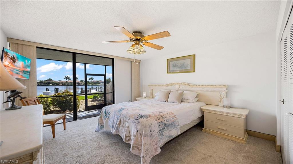 601 Seaview Court, Unit C106 Marco Island, FL 34145 - Photo 14 of 42 Bedroom with expansive windows, access to exterior, a textured ceiling, a water view, and carpet