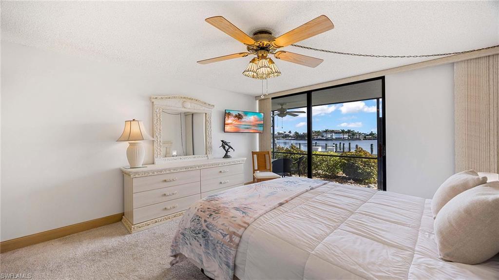 601 Seaview Court, Unit C106 Marco Island, FL 34145 - Photo 15 of 42 Bedroom with a textured ceiling, a ceiling fan, light colored carpet, access to exterior, and floor to ceiling windows