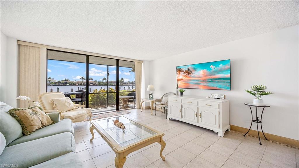 601 Seaview Court, Unit C106 Marco Island, FL 34145 - Photo 2 of 42 Living area with floor to ceiling windows, a textured ceiling, and light tile patterned flooring