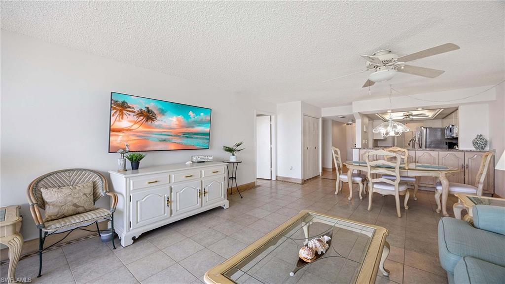 601 Seaview Court, Unit C106 Marco Island, FL 34145 - Photo 3 of 42 Living area with a textured ceiling, light tile patterned floors, a ceiling fan, and a chandelier
