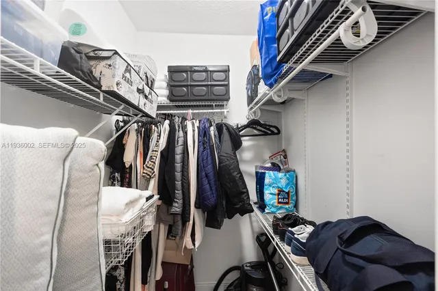 a view of walk in closet with clothes and shoes