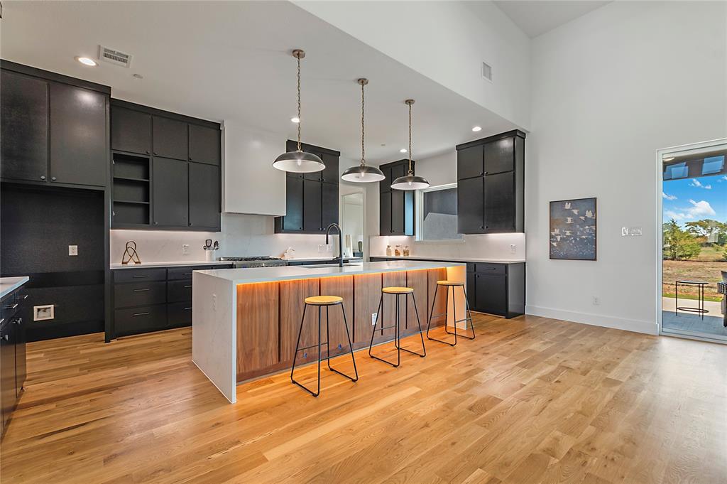 430 Whispering Way Red Oak, TX 75154 - Photo 16 of 40 Kitchen featuring wood-finish flooring, dark cabinetry, and a central island with integrated lighting